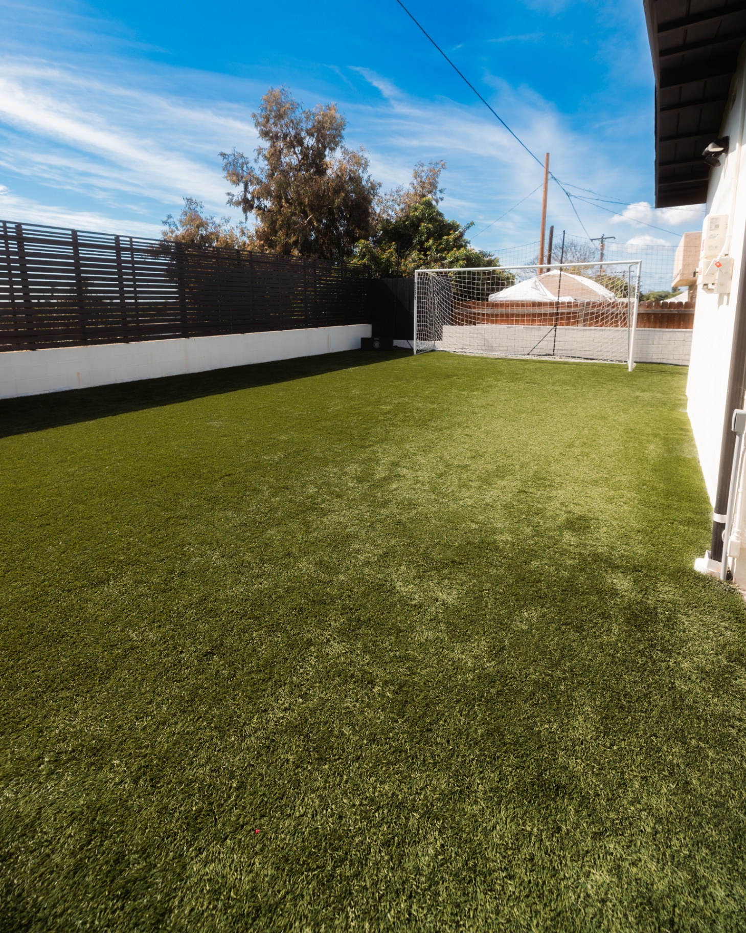 Artificial turf lawn bordered by a horizontal slat fence