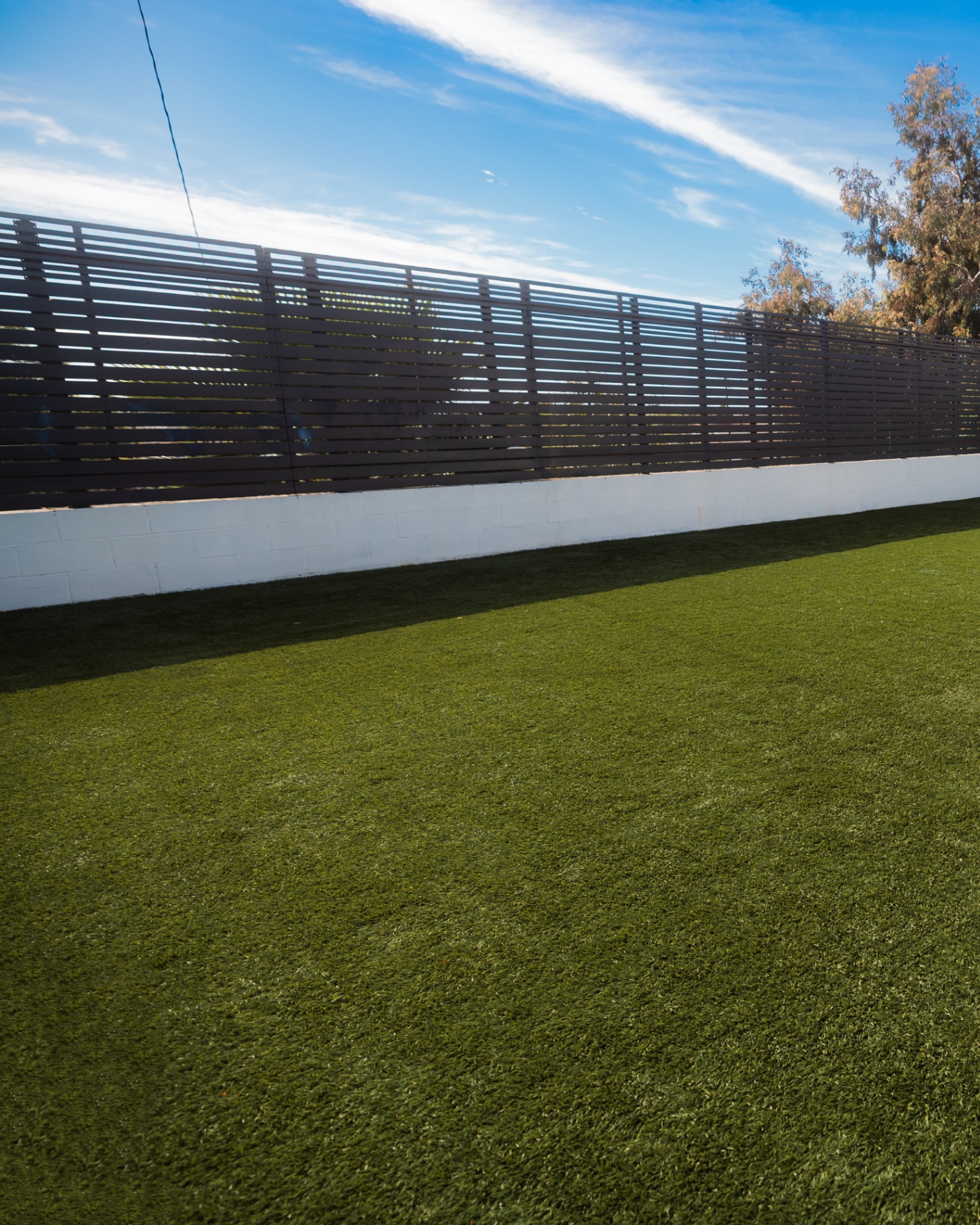 Artificial turf lawn bordered by a horizontal slat fence