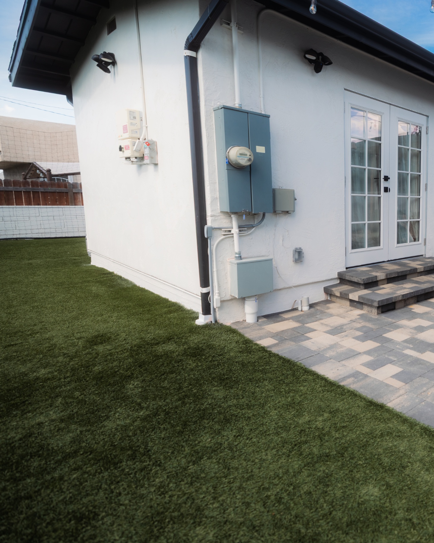 Artificial turf meeting a gray paver landing at French doors
