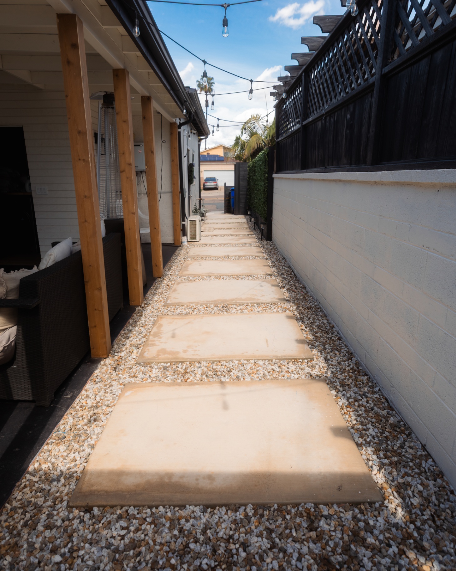 Square concrete stepping pads set in gravel along a side yard