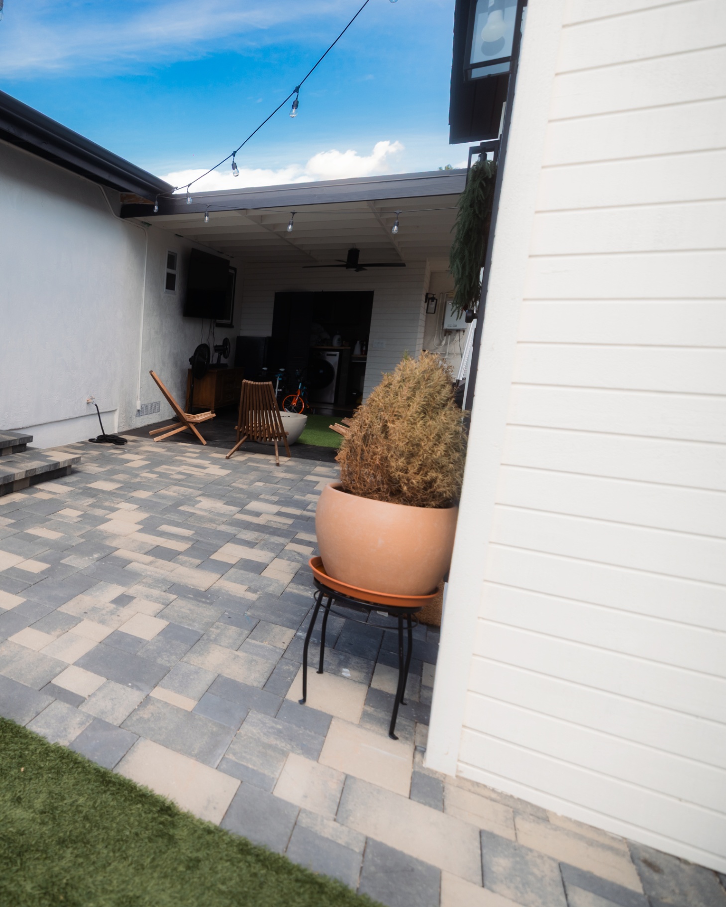 Gray paver patio between a home and covered seating area