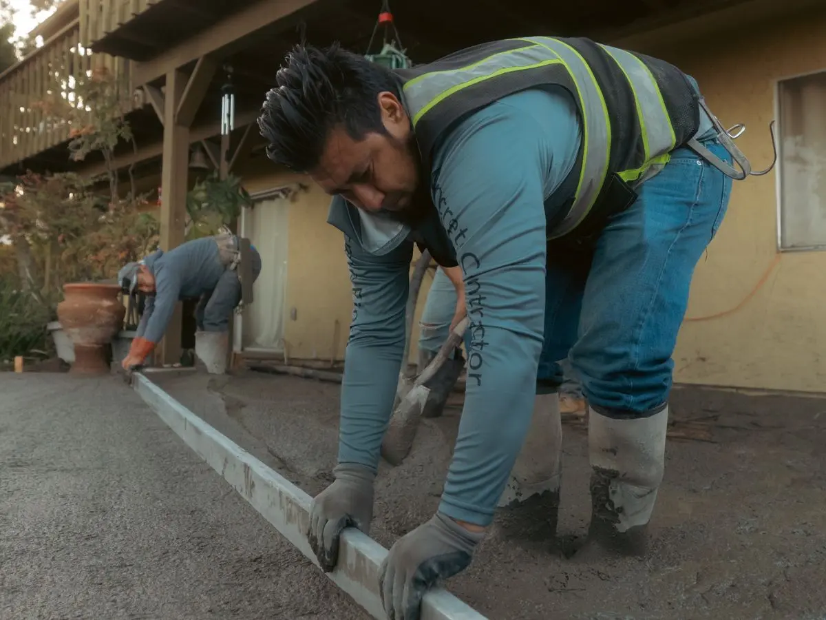 Alejandro Olivo screeding a fresh concrete pour in a San Diego backyard
