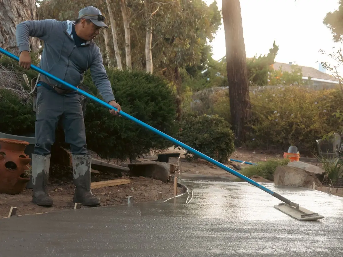 Concrete finisher bull floating a freshly poured slab at sunset