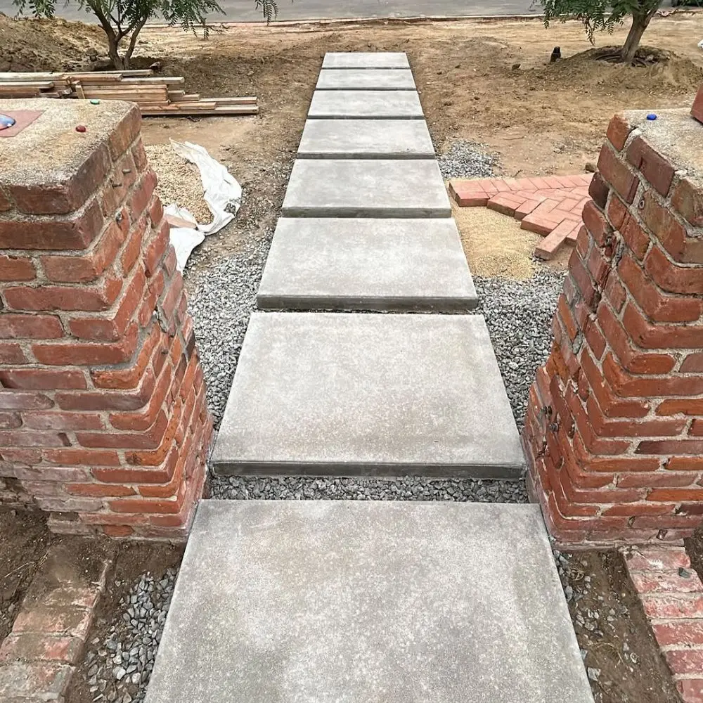Poured concrete step pads set in gravel between two brick pillars