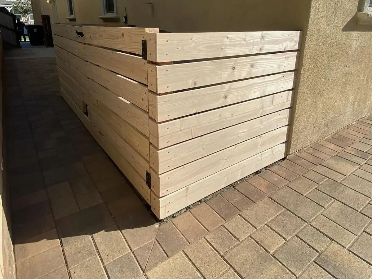 Horizontal cedar slat privacy screen built over a paver walkway alongside a home